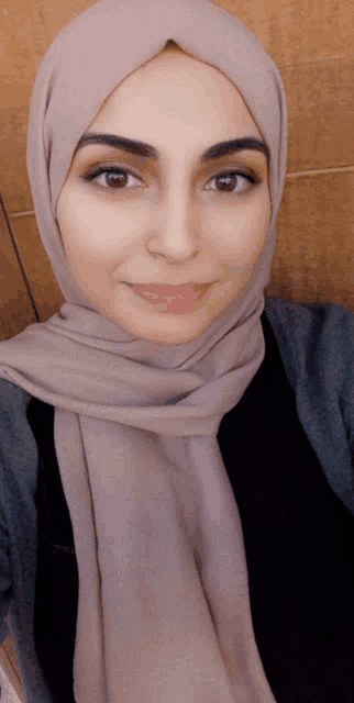 a woman wearing a scarf and a hijab smiles for the camera