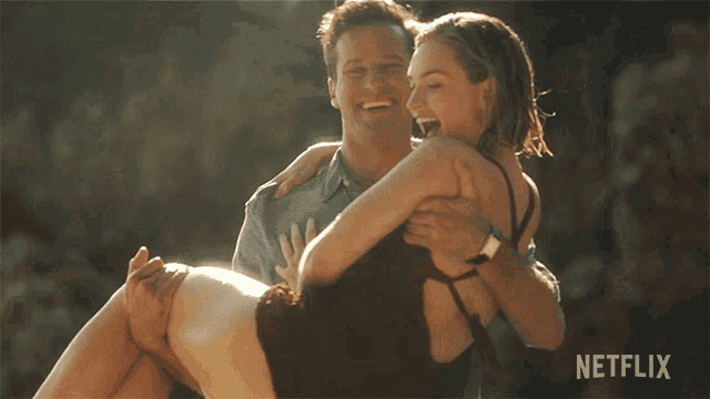 a man is carrying a woman in his arms with a netflix logo in the background
