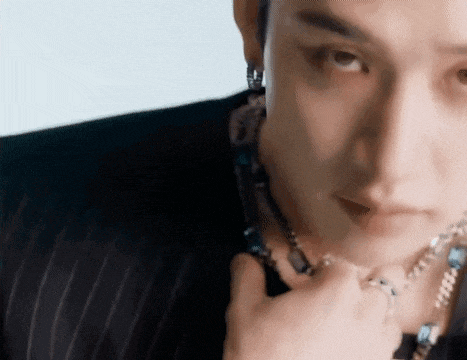 a close up of a man wearing a black suit and a necklace .