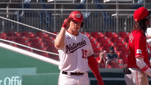 a baseball player wearing a nationals uniform salutes