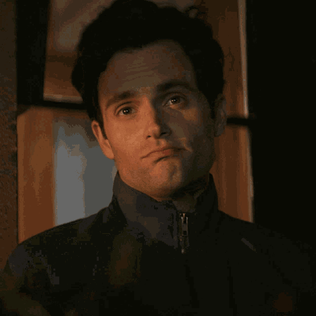 a man wearing a blue jacket is looking out a window