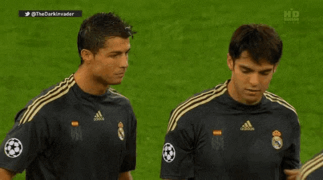 two soccer players wearing adidas jerseys are standing next to each other on a field