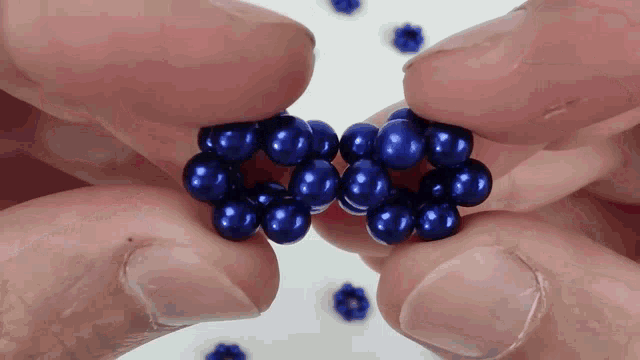 a person is holding a cluster of blue beads between their fingers