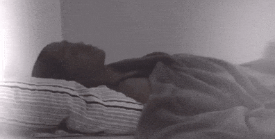 a person is laying on a bed with a striped pillow and blanket