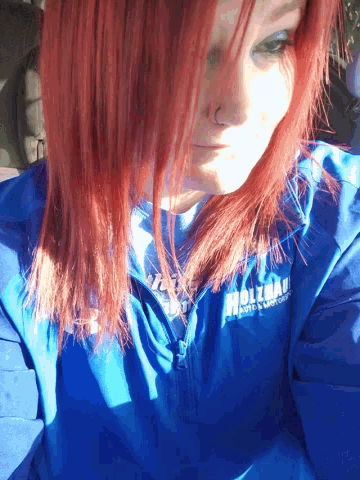a woman with red hair is wearing a blue shirt that says ' wolverine ' on the front