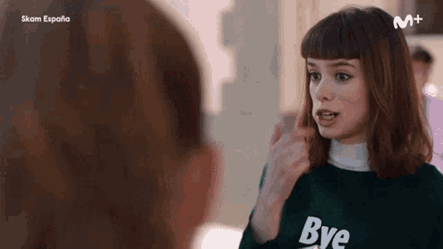 a woman wearing a green bye sweater is talking to another woman