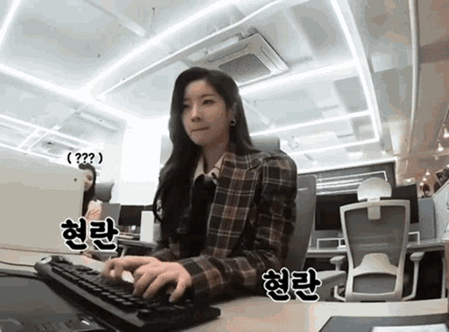 a woman sitting at a desk typing on a keyboard
