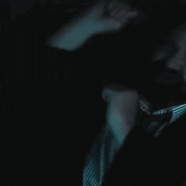 a man with a beard wearing a striped shirt and tie in the dark .