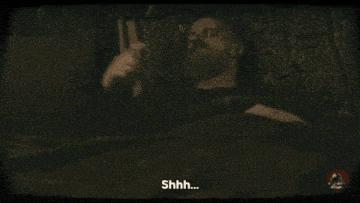 a group of people are sitting in a dark room and one of them is saying " shh "