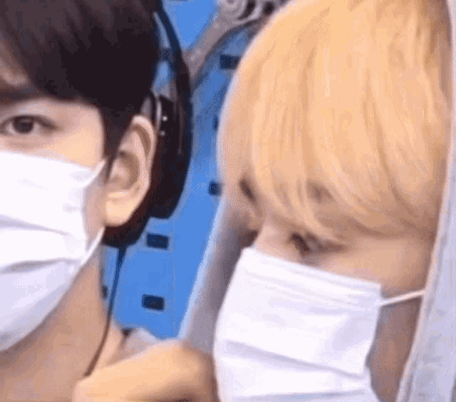 a man wearing a mask and headphones is standing next to another man wearing a mask .