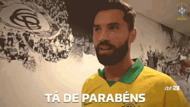 a man with a beard wearing a yellow and green shirt that says ta de parabéns