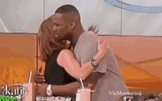 a man and a woman are hugging and kissing in front of a sign that says vicmarrowind