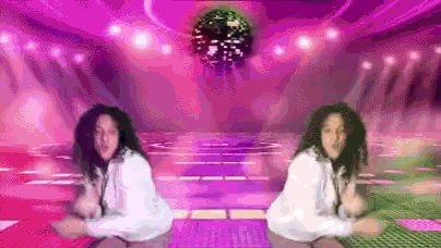 two women are dancing on a dance floor in front of a disco ball