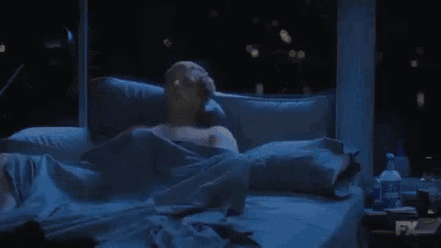 a man is laying on a bed with fx written on the corner of the bed