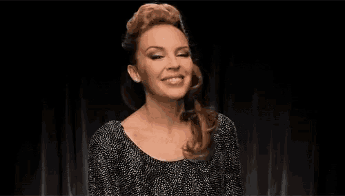 a woman in a black and white dress is covering her mouth with her hand and smiling .