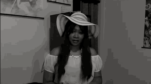 a woman wearing a white hat and a white shirt is standing in a room .