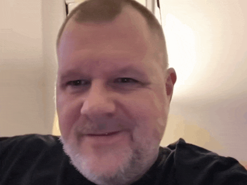 a man with a beard wearing a black shirt smiles for the camera