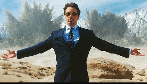 a man in a suit and tie is standing with his arms outstretched in front of a mountain .
