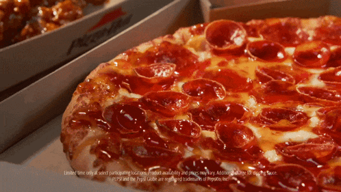 a pepperoni pizza sits next to a box of chicken