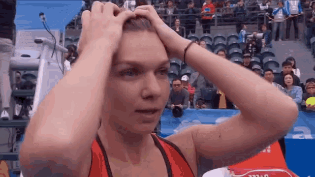 a woman in a red shirt is holding her head while a crowd watches .