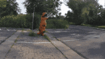 a person in a t-rex costume walks down a sidewalk
