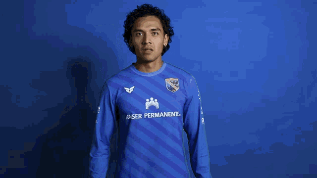 a man in a blue kaiser permanente jersey holds up a red card