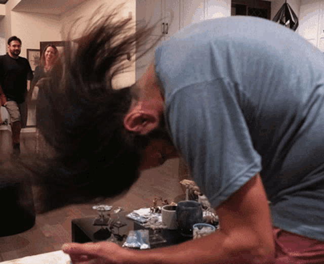 a man in a blue shirt has his hair blowing in the air