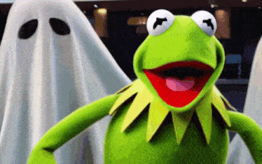 kermit the frog is standing in front of a ghost .