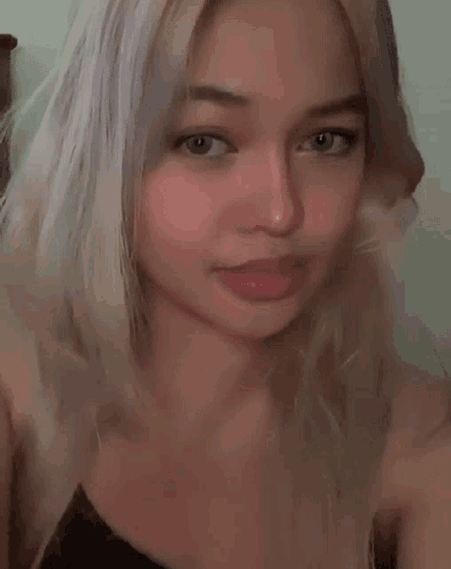 a close up of a woman taking a selfie with her hair in the air .
