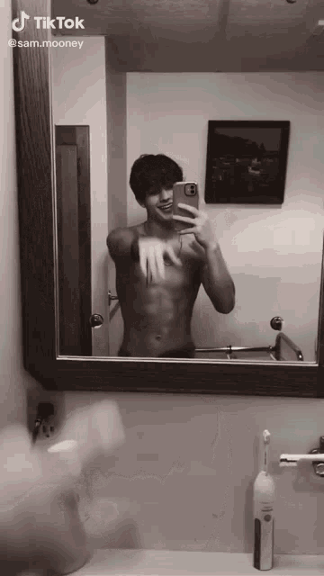 a shirtless man taking a picture of himself in a bathroom mirror with the hashtag tiktok