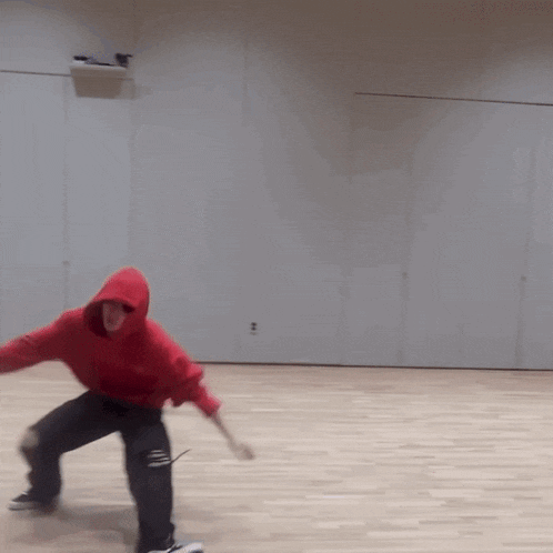 a person wearing a red hoodie is dancing on a wooden floor