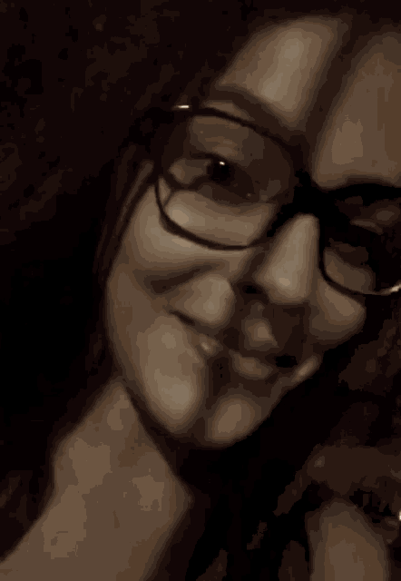 a close up of a woman wearing glasses and a ring on her finger