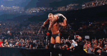 a wrestler is carrying another wrestler on his shoulders in front of a crowd ..