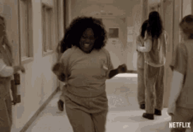 a woman is dancing in a hallway while a group of women are standing behind her .