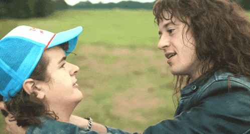 a man wearing a blue hat and a woman wearing a blue jacket are hugging