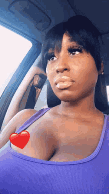 a woman is sitting in a car with a heart on her chest .