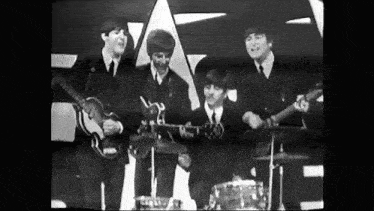a black and white photo of the beatles playing guitars on a stage .