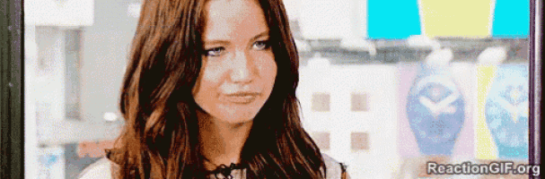 a woman with long brown hair is making a funny face while looking at the camera .