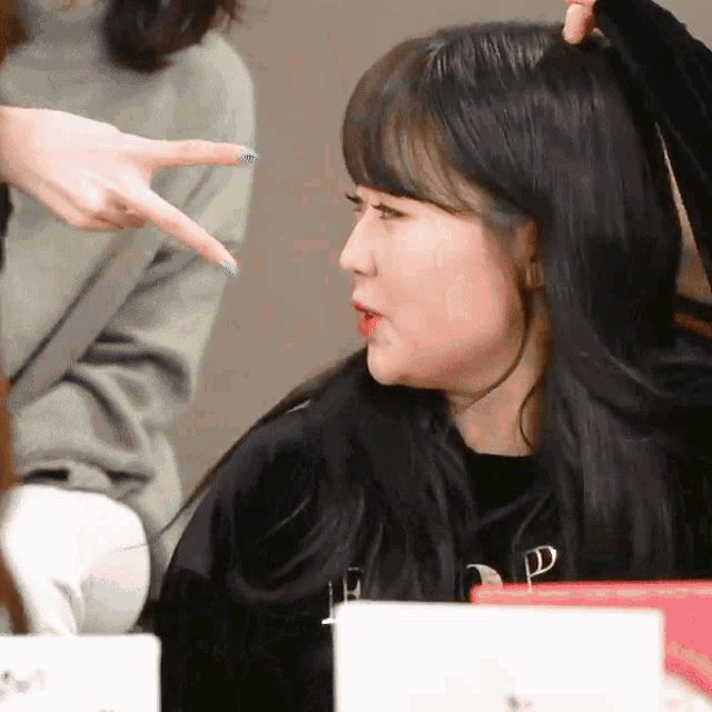 a woman in a black shirt with the letter p on it is being touched by another woman 's hand