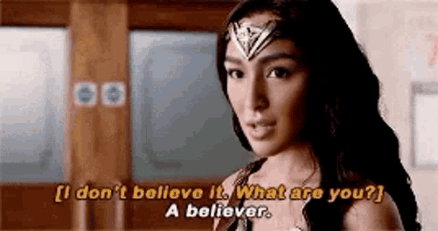 a woman in a wonder woman costume is talking to a man in a hallway .