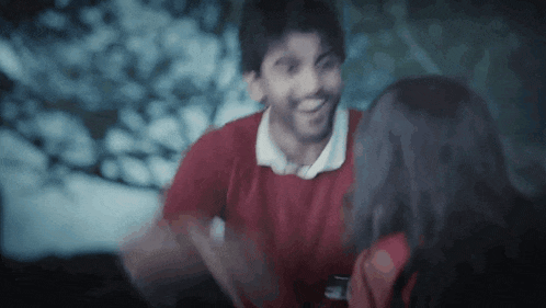 a man in a red shirt is hugging a woman in a dark room