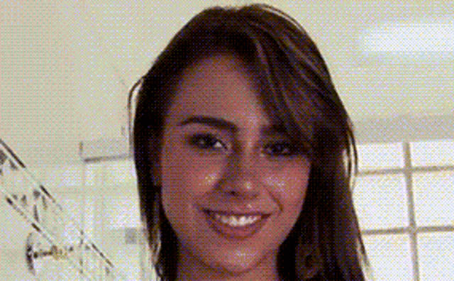 a close up of a woman 's face with a blurred background and a smile .