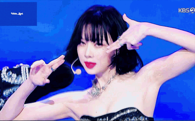 a woman in a black dress is making a peace sign with her fingers