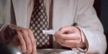 a man in a suit and tie is holding a piece of paper in his hands .