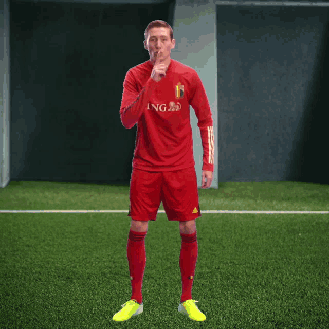 a soccer player wearing a red ing jersey holds his finger to his mouth