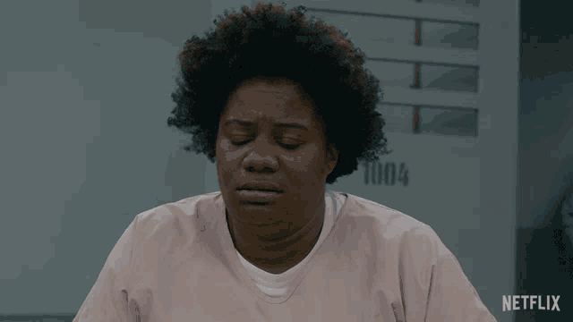 a woman in a pink scrub is sitting in front of a sign that says 1004