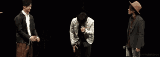 a man in a striped jacket is singing into a microphone on stage