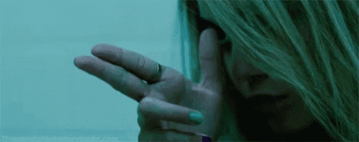 a close up of a woman covering her face with her hand in a dark room .