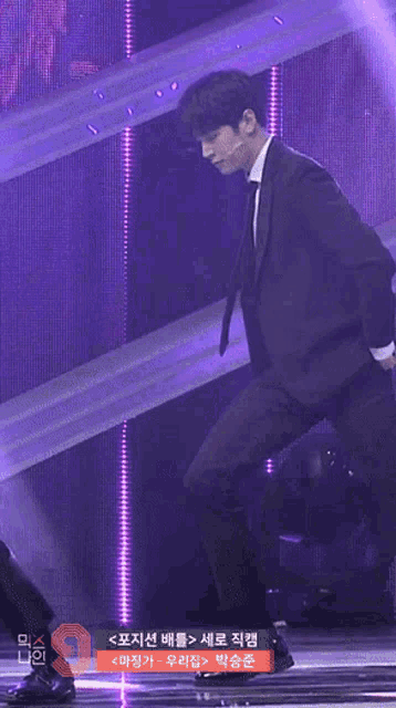 a man in a suit and tie is kneeling on a stage