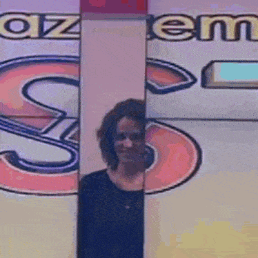 a woman is standing in front of a sign that has the letter s on it .